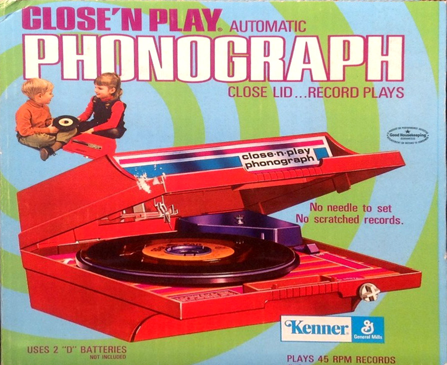 A vintage toy advertisement features two children playing with a bright red plastic battery-operated Close'N Play automatic phonograph. You put a 45 record in the box and close the lid and it started playing automatically. The needle was built into the lid.